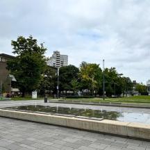a fountain in a park with trees and buildings