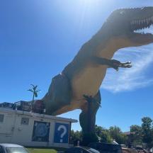 eine Statue eines Dinosauriers, die auf einem Parkplatz steht