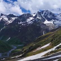a snowy mountain range with a river in front of it