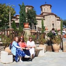 tres dones assegudes en un banc davant d'un edifici