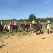 a group of people riding horses on a dirt road