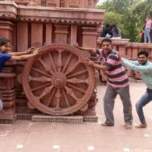 a group of three people playing with a wooden wheel