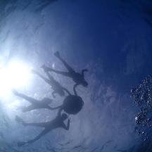 two people swimming in a pool with the sun in the water