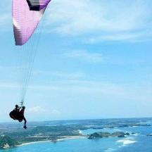 a person is hanging from a parachute over the ocean