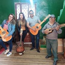 ryhmä ihmisiä seisoo huoneessa kitaroiden kanssa