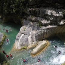 Skupina lidí sjíždících řeku na raftech v jeskyni
