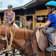 a young boy riding on a horse with a woman