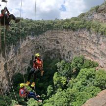 a group of people on a zip line on a cliff