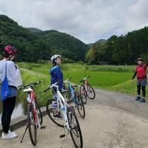 three women standing on a path with their bikes