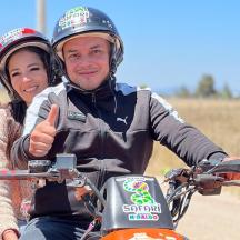 un bărbat și o femeie pe o motocicletă care ridică degetul mare