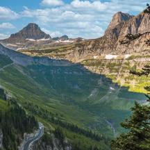 a winding road in a mountain valley with trees