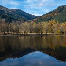 a lake with trees and mountains in the background
