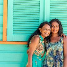 two women standing in front of a blue house