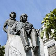 a statue of a man sitting on top of a building