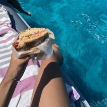 a person sitting on a chaise lounge eating a sandwich