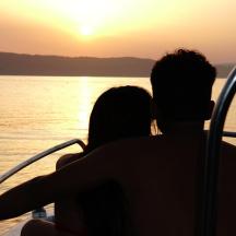 ein Paar sitzt auf einem Boot und beobachtet den Sonnenuntergang