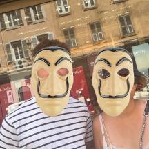two people with masks on their faces in front of a building