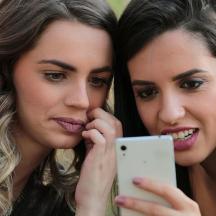 two women are looking at a cell phone