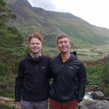 two men are standing in front of a mountain