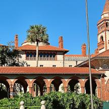 a large brick building with a clock tower with palm trees