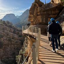 a group of people walking on a walkway on a canyon