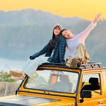 a man and woman sitting on top of a car