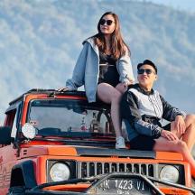two people sitting on the top of a jeep