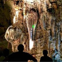 Un grupo de personas de pie frente a una cueva.