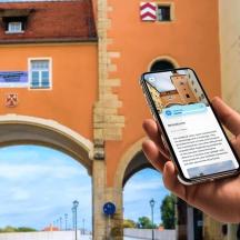 una persona che tiene in mano un telefono cellulare davanti a un edificio