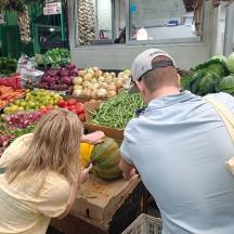 a man and a woman looking at produce in a market