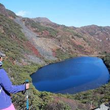a woman standing on top of a mountain looking at a lake