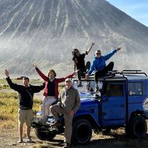 a group of people sitting on top of a jeep in front of a mountain
