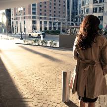 a woman is standing on a sidewalk in a city