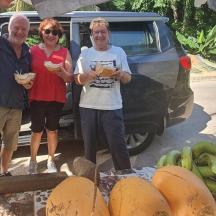 three people standing in front of a table of bananas