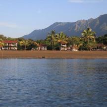 a body of water with houses and palm trees and mountains