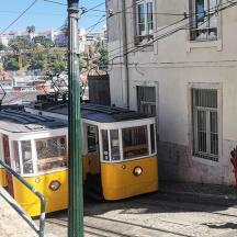 a yellow tram is parked next to a building