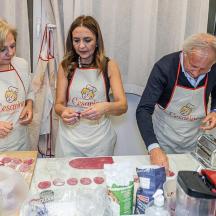 ein Mann und zwei Frauen in einer Küche, die Essen zubereiten