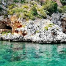 a rocky shore with turquoise water in front thereof