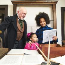 ein Mann und ein Mädchen stehen neben einem Tisch mit Papieren