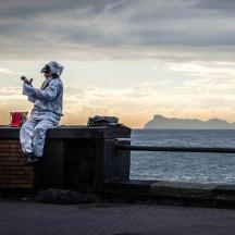 a man sitting on a wall taking a picture of the ocean