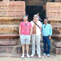 a group of three men standing in front of a temple