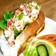 isang sandwich sa isang puting plato na may lettuce at isang kamatis
