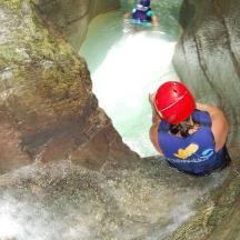 una dona puja per una roca en una cascada