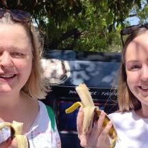 two women are smiling while holding peeled bananas