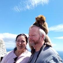 a man and a woman standing on a rock with a monkey on his head