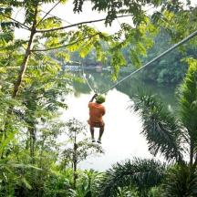 a man on a zip line over a river in the jungle