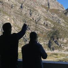 двоє людей стоять на виступі та дивляться на гору