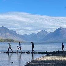 a group of people walking on the shore of a lake