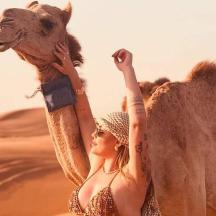 a woman is holding a camel in the desert