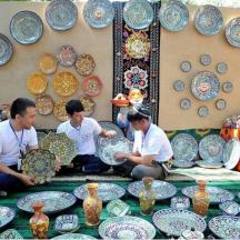 a group of men sitting in front of a display of pottery